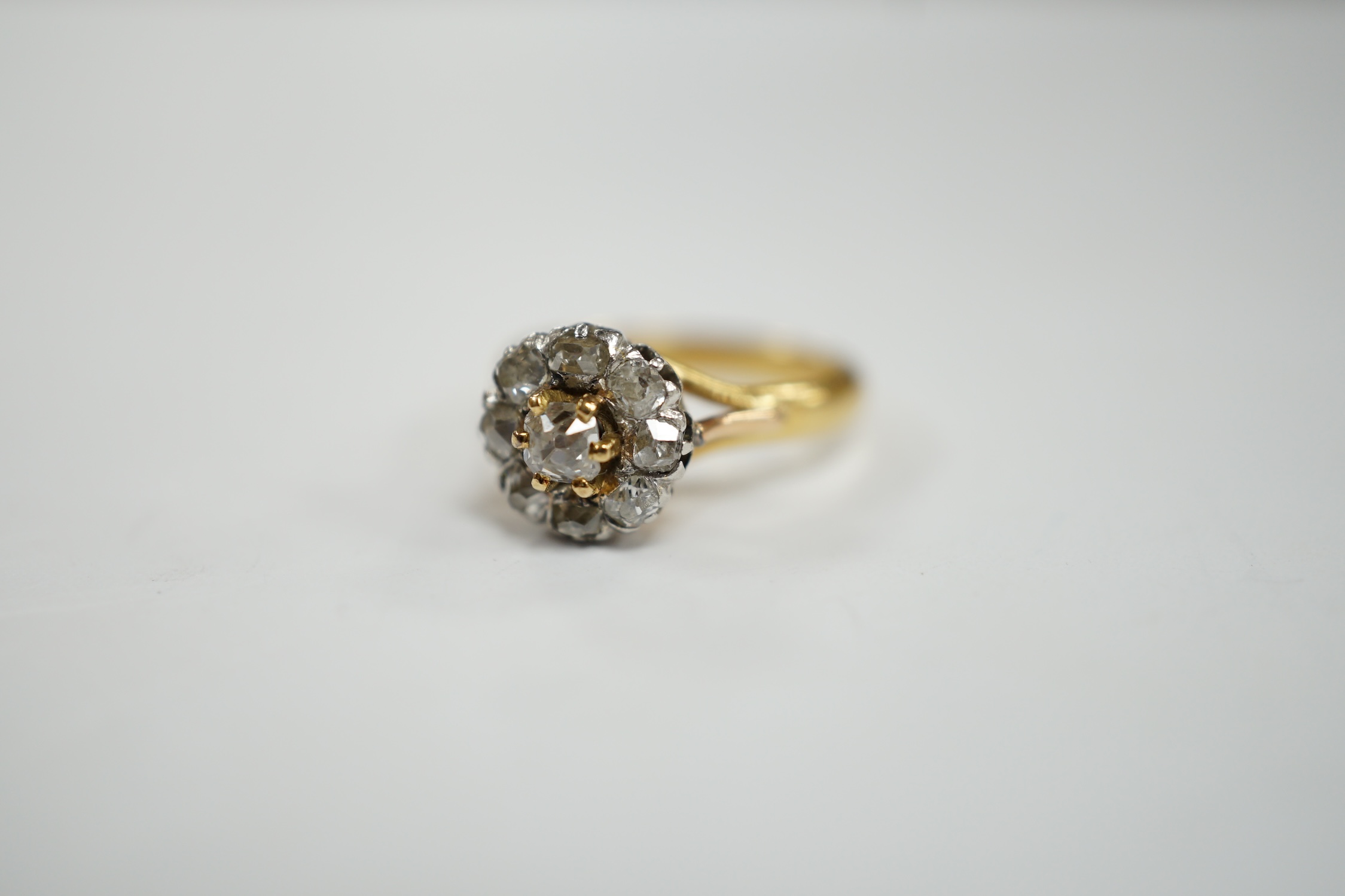 An early 20th century French 18k and nine stone diamond set flower head cluster ring, size G, gross weight 3.4 grams.